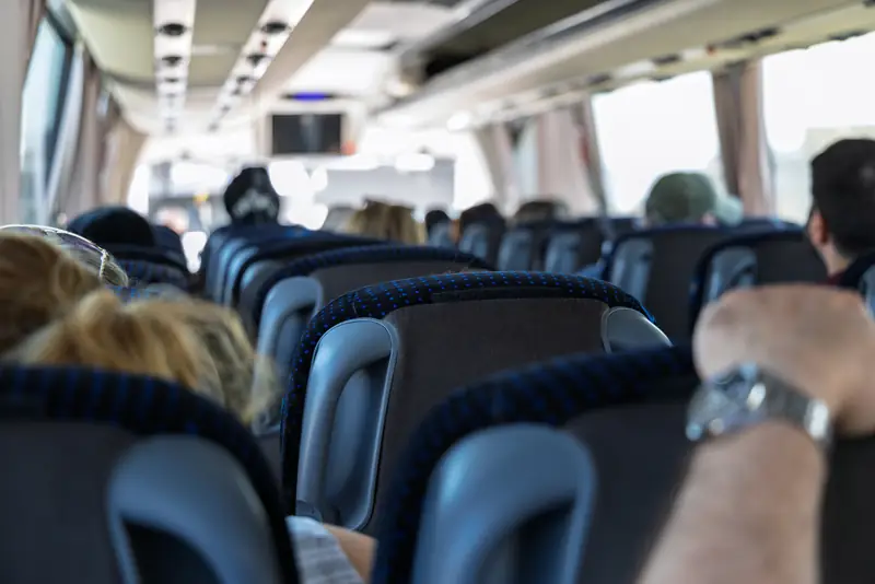 Fahrgäste sitzen in einem Reisebus, Blick von hinten durch den Gang
