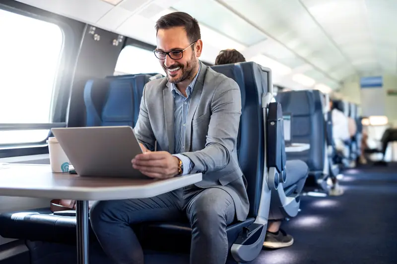 Lächelnder Mann arbeitet im Zug am Laptop