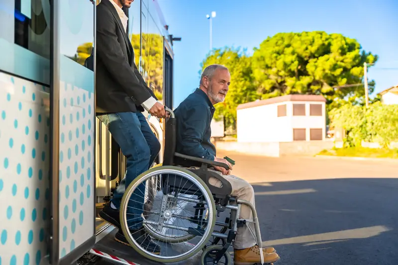 Mann im Rollstuhl fährt über die ausgeklappte Rampe aus einem Bus
